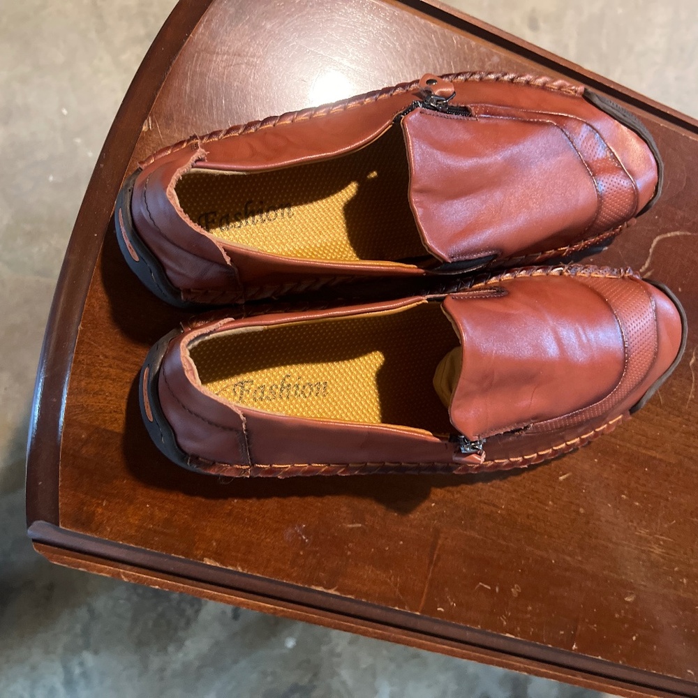 Men hand stitching zipper on leather shoes